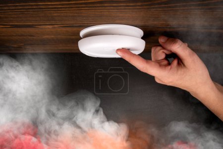 Foto de Detector de humo blanco y mano de mujer. Humo colorido. - Imagen libre de derechos