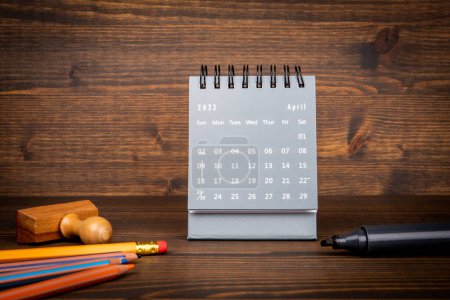 Photo for 2023 April. Desk calendar and office supplies on wooden texture background. - Royalty Free Image