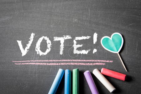 VOTE. text and colored pieces of chalk on a dark textured blackboard.