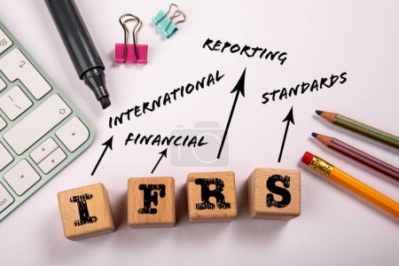 NIIF - Normas internacionales de información financiera. Bloques de madera en una mesa de oficina blanca.