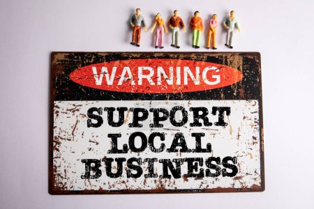 Unterstützung lokaler Unternehmen. Warnschild mit Text und menschlichen Miniaturfiguren auf weißem Hintergrund.