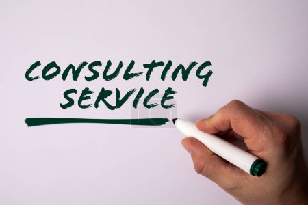 CONSULTING SERVICE Concept. A hand with a marker writes text on a light background.