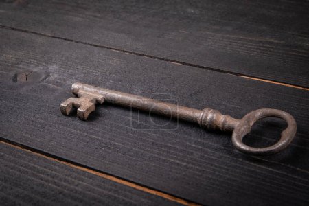 Photo for Old antique rusty key on dark wood texture background. - Royalty Free Image