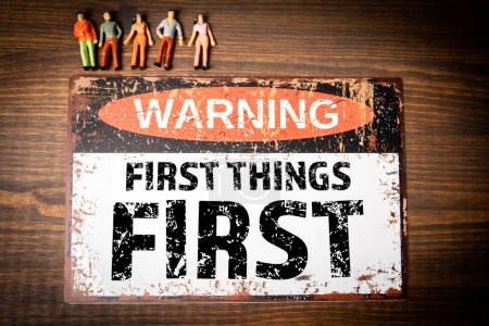 First things first. Warning sign with text on wood texture background.
