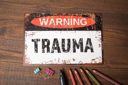 TRAUMA. Warning sign with text on wood texture background.