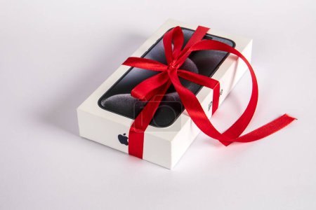 Photo for Sigulda, Latvia - October 18, 2023: Box of the Iphone 15 Pro on on a white background. Gift with a red ribbon - Royalty Free Image