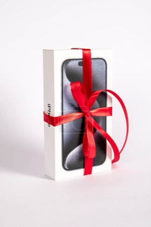 Photo for Sigulda, Latvia - October 18, 2023: Box of the Iphone 15 Pro on on a white background. Gift with a red ribbon - Royalty Free Image