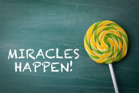 Téléchargez les photos : Miracles Happen Concept. Des bonbons sur un bâton, sucette. Arrière-plan tableau. - en image libre de droit