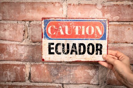 Téléchargez les photos : Équateur. Signe de prudence dans une main de femme sur un fond de brique. - en image libre de droit