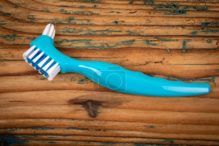 Denture toothbrush on a wooden background. Effective cleaning of teeth and gums.