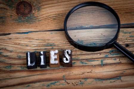 LIES. Alphabet letters on wood texture background.