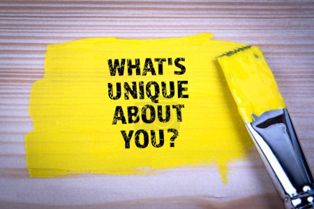 Whats Unique About You. Yellow paint and paint brush on wooden texture background.