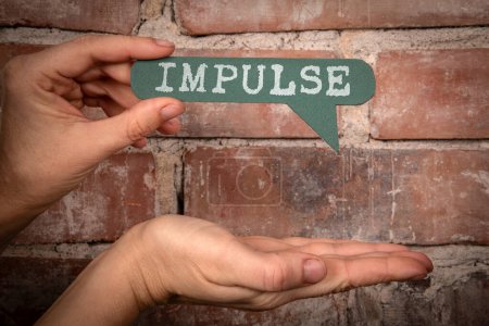 Impulse. Green speech bubble with text on a red brick background.