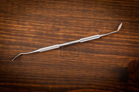 Photo for Dental hygienist instrument on a dark wooden background. Learning and professionalism. - Royalty Free Image