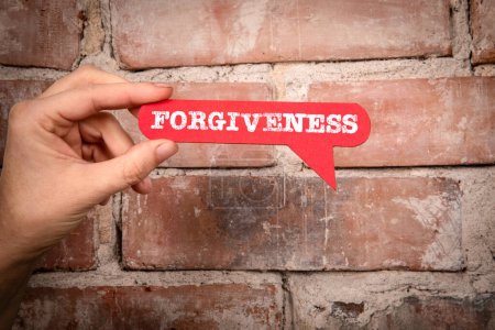 Forgiveness. Red speech bubble with text on a red brick background.