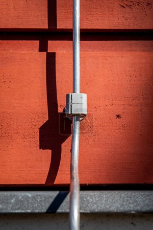 Lightning rod on the wall of a red wooden building. Architecture and structures.
