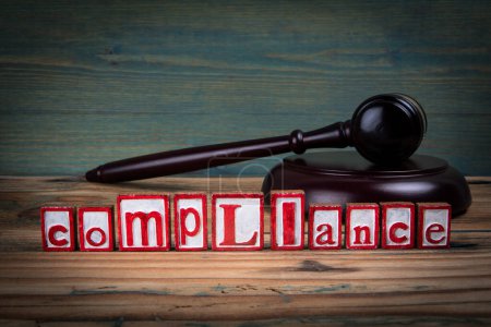 COMPLIANCE. Red alphabet letters and judges gavel on wooden background. Laws and justice concept.