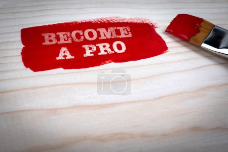 Become a Pro. Red paint and paint brush on wooden texture background.