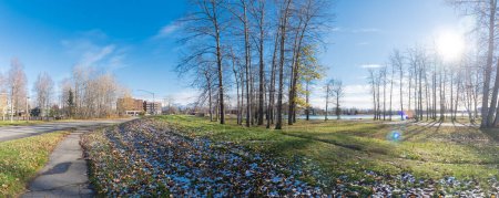 Téléchargez les photos : Vue panoramique sentier au bord du lac à flanc de colline avec des feuilles brunes tombées couvertes de neige, des arbres dormants sous un ciel bleu nuageux ensoleillé dans le lac Spenard, Anchorage. Complexe d'appartements et montagne de Chugach - en image libre de droit