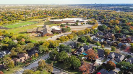 Photo for Aerial view school district with football field, elementary and middle schools in upscale residential neighborhood with downtown Dallas and Las Colinas in distance background. Beautiful autumn leaves - Royalty Free Image