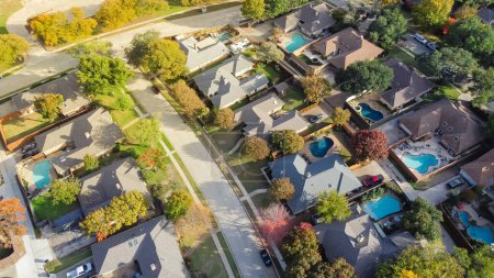 Photo for Upscale single family home with swimming pool and colorful fall foliage near Dallas, Texas, America. Aerial view an established suburban residential neighborhood bright autumn leaves, large street - Royalty Free Image
