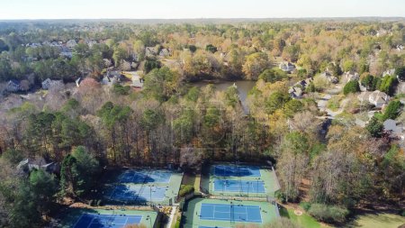 Photo for Upscale subdivision sprawl leading with tennis court complex, lakeside two story houses leading to horizontal line suburbs Atlanta, Georgia, USA. Aerial view recreational community sport facility - Royalty Free Image