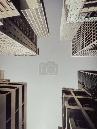 Photo for Toned photo lookup view skyscrapers and corporate office buildings under clear blue sky along Main Street in Downtown Dallas, TX, USA. Wide angle upward perspective of high-rise tower in metro complex - Royalty Free Image