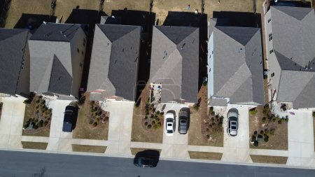 Téléchargez les photos : Vue aérienne à 90 degrés de toits simples sur des maisons résidentielles flambant neuves de deux étages avec garage avant dans un quartier haut de gamme près d'Atlanta, Géorgie, États-Unis. Haut de gamme HOA maison de banlieue pelouse bien taillée - en image libre de droit