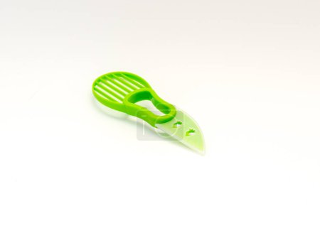 Photo for Green BPA free all-in-one avocado slicer tool knife in plastic guard blade cover and non-slip silicone handle isolated on white background. Dishwasher safe cutter and pitter utensil for avocado - Royalty Free Image
