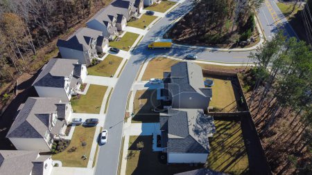 Téléchargez les photos : Nouvelles maisons de banlieue avec toit en bardeaux, cour bien garnie, garage porte d'entrée près des bois luxuriante zone des arbres verts et route de service à l'extérieur d'Atlanta, Géorgie, États-Unis. Maisons avec vue aérienne dans la colonie planifiée - en image libre de droit
