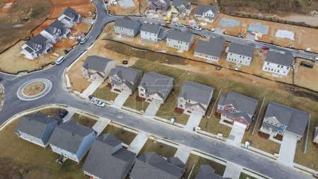 Roundabout traffic circle in new development residential neighborhood with two story houses under construction, building envelope in Flowery Branch, Georgia, USA. Aerial high density suburban homes