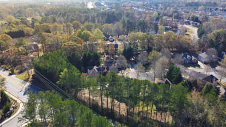 Téléchargez les photos : Lignes électriques à haute tension dans le nouveau quartier résidentiel de développement entouré d'arbres verts luxuriants, rangée de maisons unifamiliales de deux étages banlieues Atlanta, Géorgie, États-Unis. Vue aérienne nouvelles maisons de banlieue - en image libre de droit