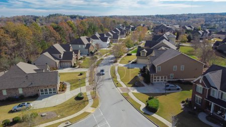 Residential street in new development neighborhood subdivision with row of two-story suburban houses and master planned community distance background near Atlanta, Georgia, USA. Aerial large homes
