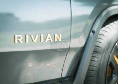 Téléchargez les photos : DALLAS, TX, USA-APR 22, 2023 : Texte de marque RIVIAN futuriste sur la porte passagers d'une camionnette R1T neuve garée à l'extérieur. Camion léger 100 % électrique à batterie - en image libre de droit