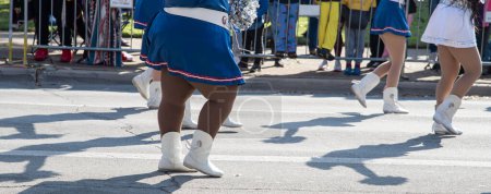 Foto de Panorama ver a diversos grupos de jóvenes animadoras en las faldas azules de vacaciones, botas blancas, pompones de papel de aluminio bailando en la calle con multitud detrás de barricadas de acero del centro de Dallas, Texas desfiles. Concepto Rally - Imagen libre de derechos