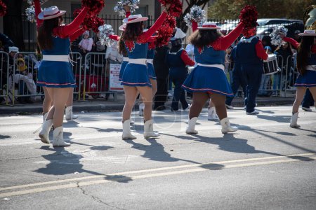 Foto de Vista trasera grupo diverso de animadoras jóvenes en faldas azules de vacaciones, botas blancas, pompones de aluminio bailando en la calle, multitud detrás de barricada de acero del centro de Dallas, Texas, EE.UU. desfiles. Concepto Rally - Imagen libre de derechos
