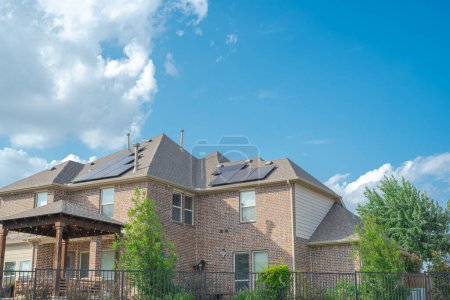 Photo for Black solar panels on shingle roofing of two story suburban residential house under sunny cloud blue sky in Flower Mound, Texas, America. Clean and renewable energy alternative power supply - Royalty Free Image