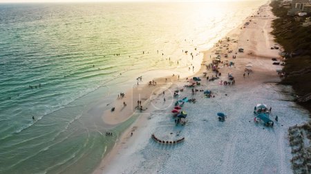 Téléchargez les photos : Coucher de soleil sur la plage de Santa Rosa avec chaises longues colorées, parasols et baignades, détente le long des plages de sable blanc, eau turquoise, magnifique nuance de bleu Floride, États-Unis. Vue aérienne - en image libre de droit