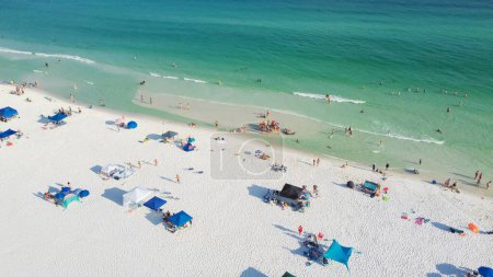 Téléchargez les photos : Belles plages de sable blanc sucre et rangée de parasol avec les gens de la famille se réunissant, se détendre, nager sur l'eau turquoise, magnifiques vagues bleues ombragées à South Walton, Floride, États-Unis. Vue aérienne - en image libre de droit
