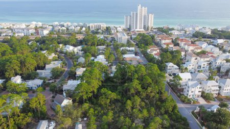 Weiße, dreistöckige Ferienhäuser, Eigentumswohnungen umgeben von üppig grünen Bäumen in Strandnähe entlang der Kreisstraße 30A, der Golfküste und der Smaragdküste Santa Rosa, Florida, USA. Luftfahrt