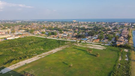Photo for Large vacant land near Farrar Canal with residential houses, duplex townhomes, lush green trees in Little Woods neighborhood toward Lake Pontchartrain in East New Orleans, Louisiana, USA. Aerial view - Royalty Free Image