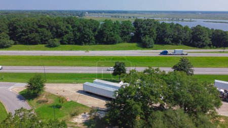 Photo for Row of semi-trucks, containers, cargo trailers parking lot Jackson County Rest Area West along Highway Intestate 10 (I-10) in Gautier, Mississippi, USA near Pascagoula River floodplain. Aerial view - Royalty Free Image
