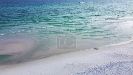 Aerial view quite beach with jus few people enjoy swimming, boating along beautiful white sandy, turquoise water, multiple shades of blue waves along Emerald Coast, Seagrove beach, Santa Rosa. USA
