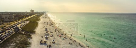 Luftaufnahme Miramar Beach mit Parkplatz direkt am Golf, geschäftige Strandaktivitäten entlang der weißen Sandküste entlang des horizontalen 98 Scenic Gulf Drive in Walton, Florida, USA. Strandgemeinde links