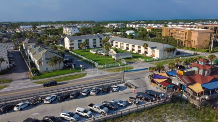 Téléchargez les photos : Parking occupé près de la rangée de condominium de plage, locations de vacances et restaurant le long de 98 Scenic Gulf Drive à Walton, Floride, Amérique. Vue aérienne plage communauté et quartier en été - en image libre de droit