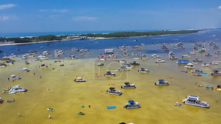 Busy Crab Island near white sandy beaches of Okaloosa Island Grass Flats in Destin, brackish water low tide and pontoons, jet skis, paddleboards, swimming, wading. Aerial Florida travel destination
