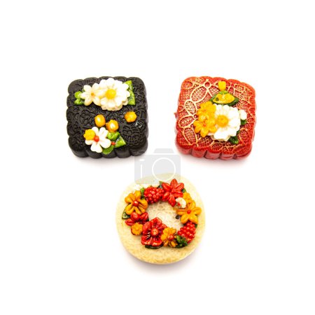 Foto de Tres tartas de luna vietnamitas con tendencia decoración de flores flotantes en 3D aisladas sobre fondo blanco, celebración del festival a mediados de otoño. Delicioso postre de panadería hecho de frijol, nuez, arroz, sésamo negro - Imagen libre de derechos