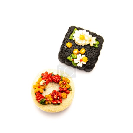 Foto de Dos tartas de luna vietnamitas con tendencia decoración de flores flotantes en 3D aisladas sobre fondo blanco, celebración del festival a mediados de otoño. Delicioso postre de panadería hecho de frijol, nuez, arroz, sésamo negro - Imagen libre de derechos