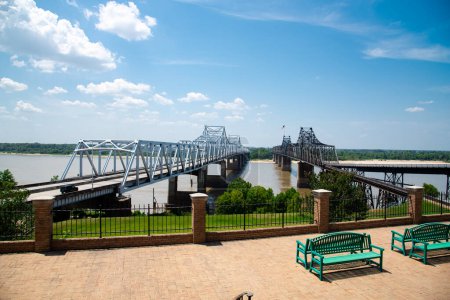 Téléchargez les photos : Point de vue avec bancs, clôture métallique surplombant le pont Twin Vicksburg, le cantilever et le transport ferroviaire transportant l'Interstate 20 et la route 80 des États-Unis à travers le fleuve Mississippi. Nuage ensoleillé - en image libre de droit