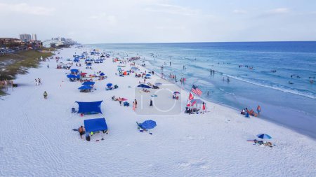 Téléchargez les photos : Miramar Beach rivage sablonneux blanc, eau turquoise, bondé de personnes nageant, détente, tentes colorées, verrière et immeubles d'hôtel de condo de grande hauteur fond, Destin, Floride. Destination de voyage - en image libre de droit